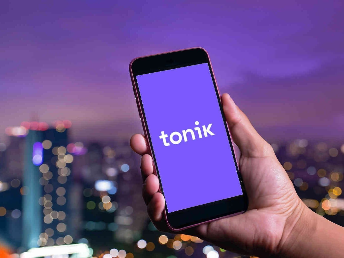 Hand holding a phone displaying Tonik logo